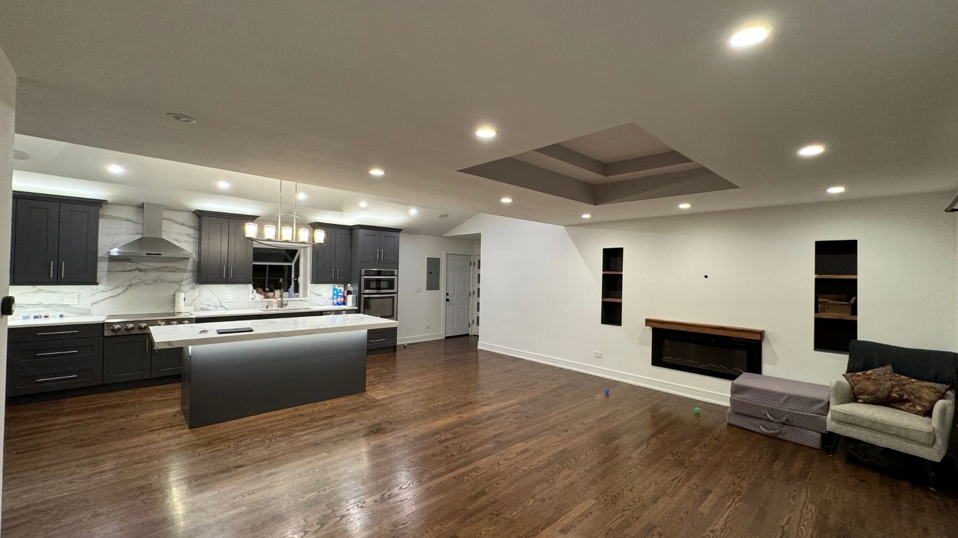Modern open-concept kitchen with gray cabinets and wood floor