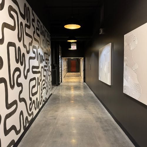 Modern hallway with abstract wall art, pendant lights, and concrete floor