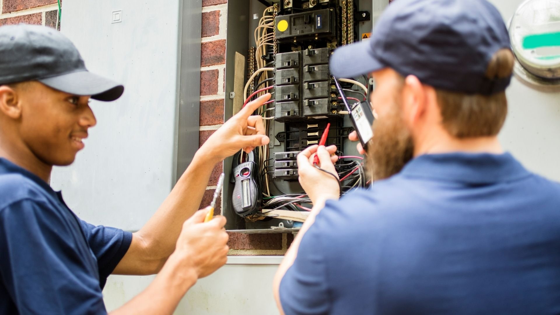 Electricians working together to inspect and repair an electrical circuit breaker panel