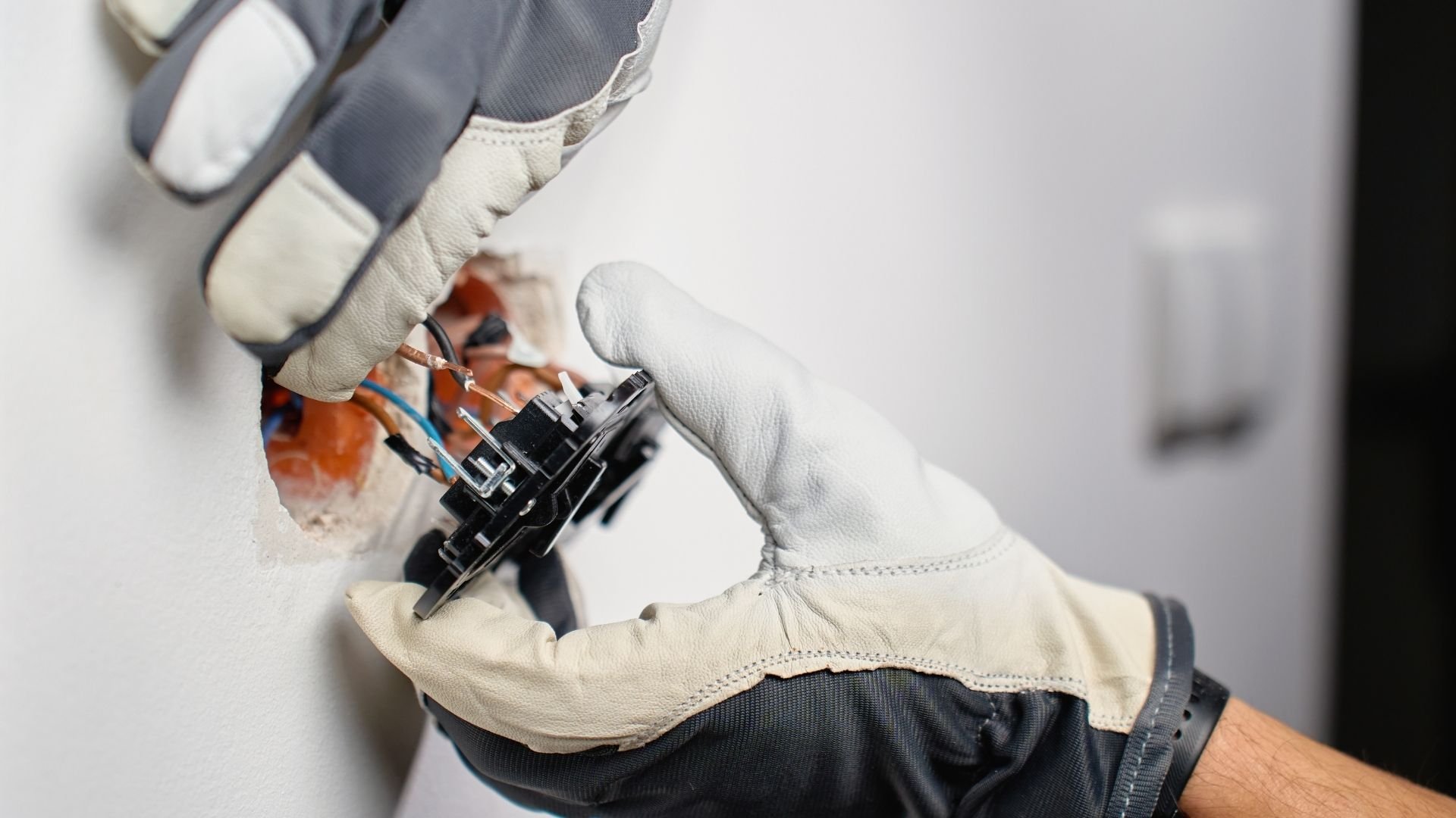 Gloved hand working on electrical or mechanical device with wires