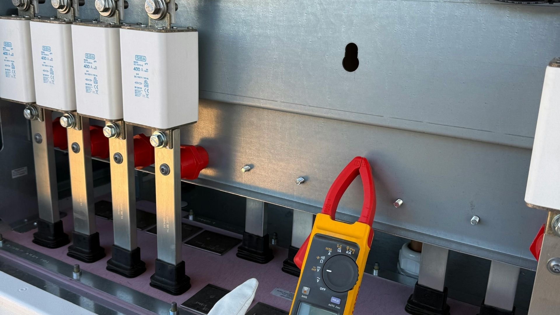 Electrical panel with white SIBA fuses and yellow digital clamp meter