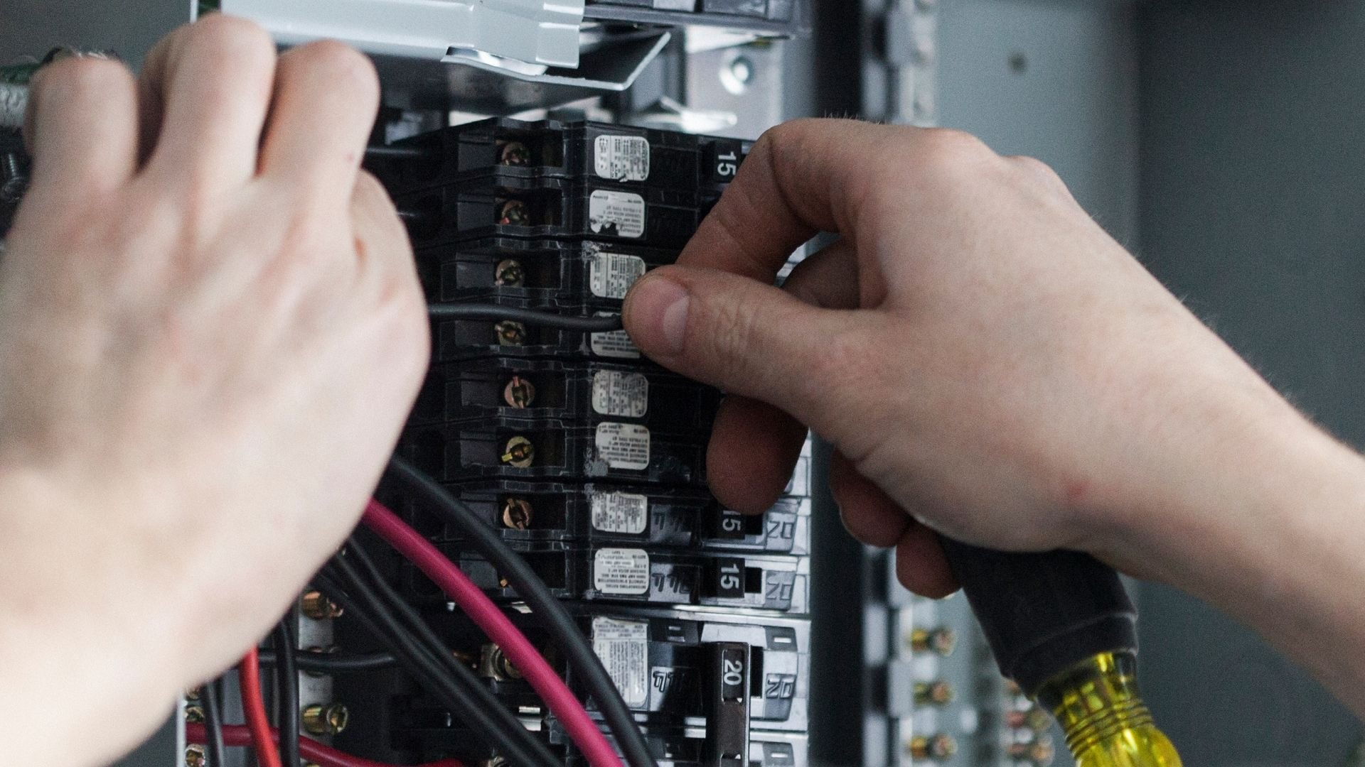 Hands working on electrical circuit breaker panel with numbered switches