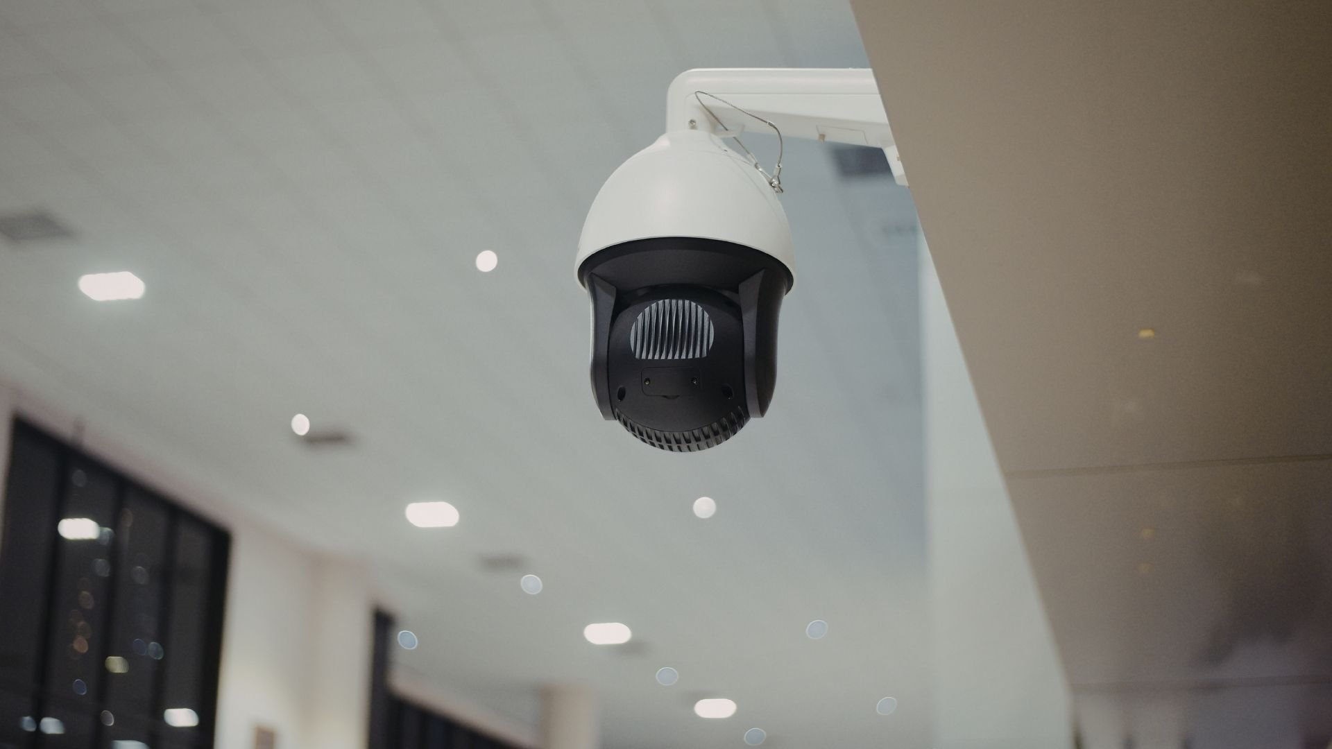White and black security camera mounted on ceiling in indoor space