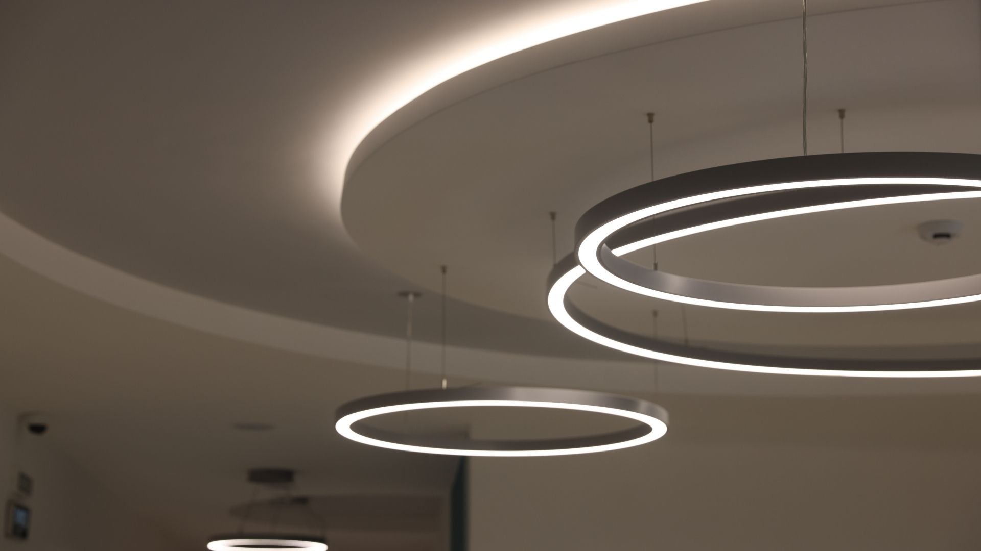 Modern circular pendant lights hanging from curved ceiling with soft glow