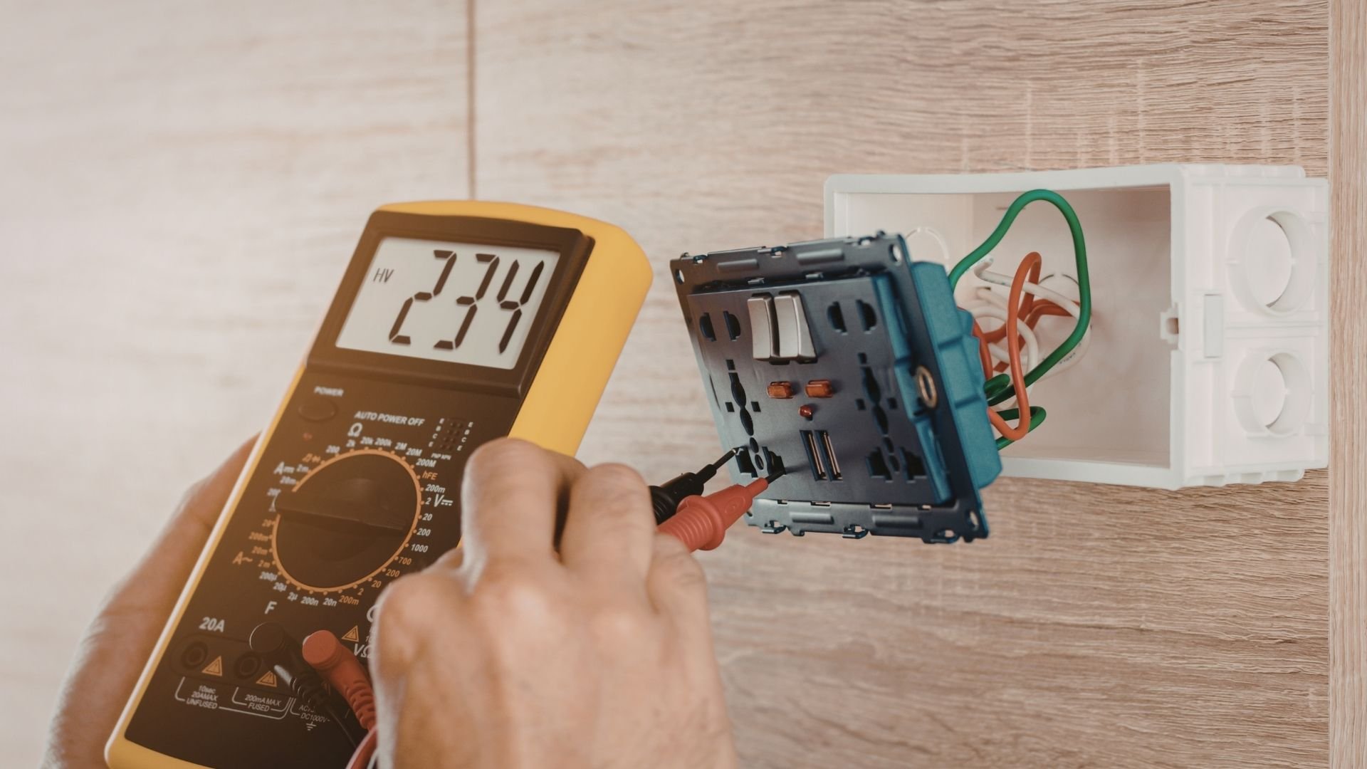 Electrician using multimeter to test voltage in electrical wall socket